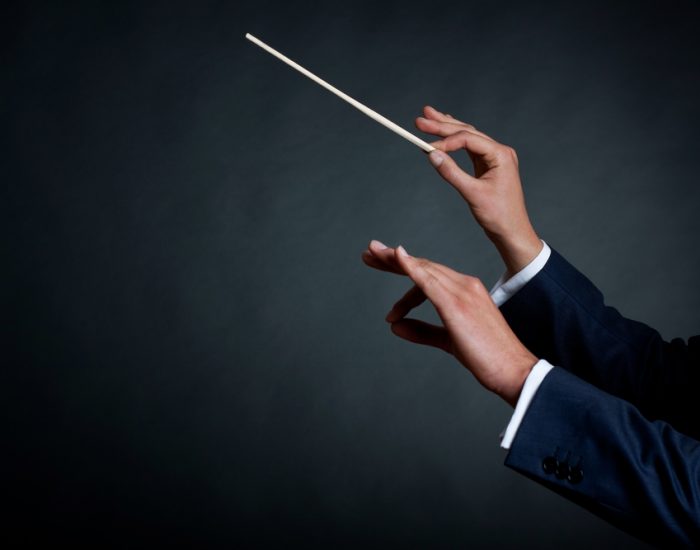image of a male orchestra conductor directing with his baton in concert